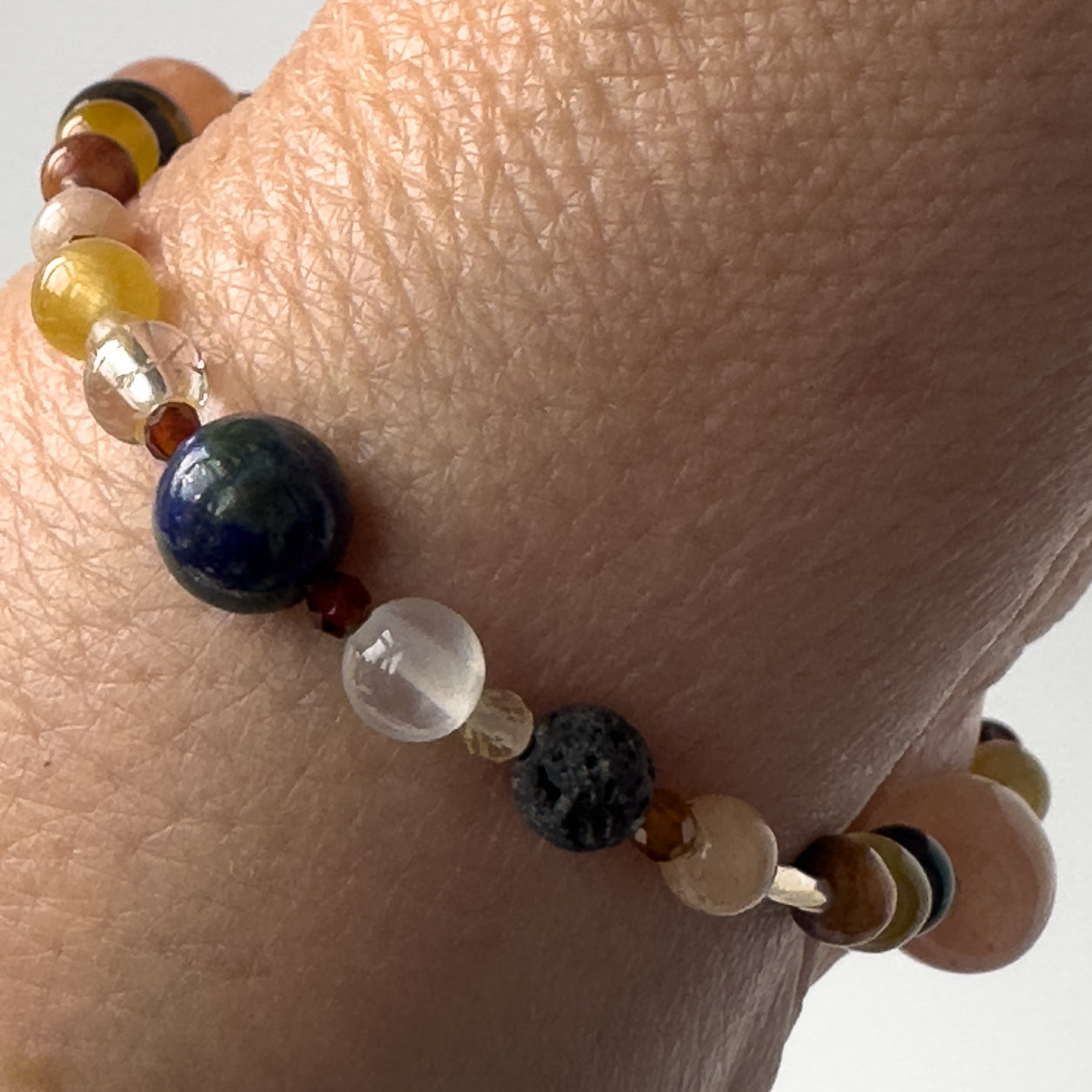 Leo Birthstone Healing Crystal bracelet for Confidence and Self-esteem on wrist showing Yellow Tiger’s Eye, Citrine, Garnet, Sunstone, Chrysocolla, Selenite, Clear Quartz and Lava Stone