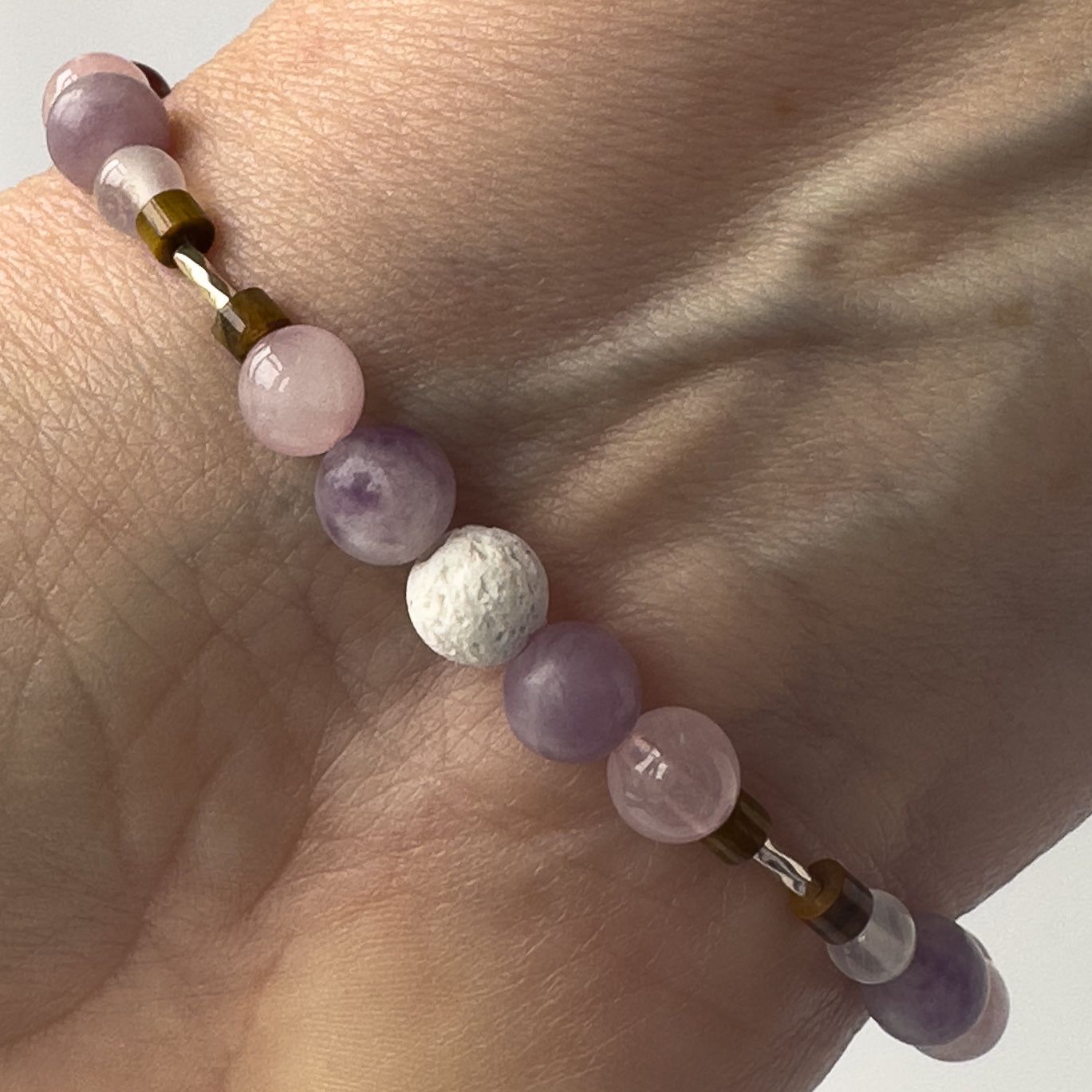 Libra Birthstone Healing Crystal bracelet for Love and Compassion on wrist showing Rose Quartz, Lepidolite, Tiger’s Eye and Lava Stone