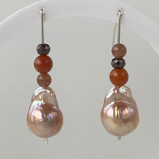Pair of earrings with large pearl drops and smaller colored beads on a white background