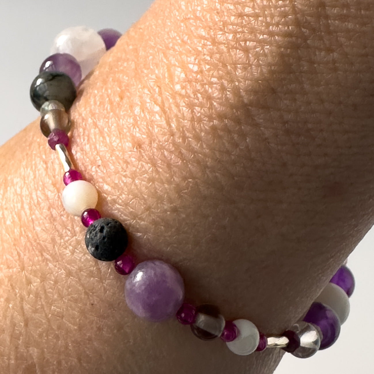 Pisces birthstone Healing Crystal bracelet for Grief & Loss support on wrist showing Lepidolite, Smoky Quartz, Moonstone, Ruby and Lava Stone