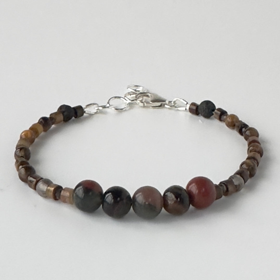 Bracelet with brown and red tones beaded design on a light grey background