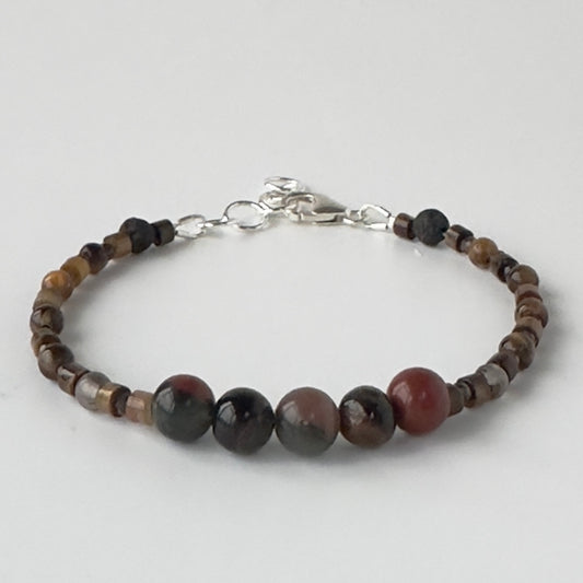 Bracelet with brown and red tones beaded design on a light grey background