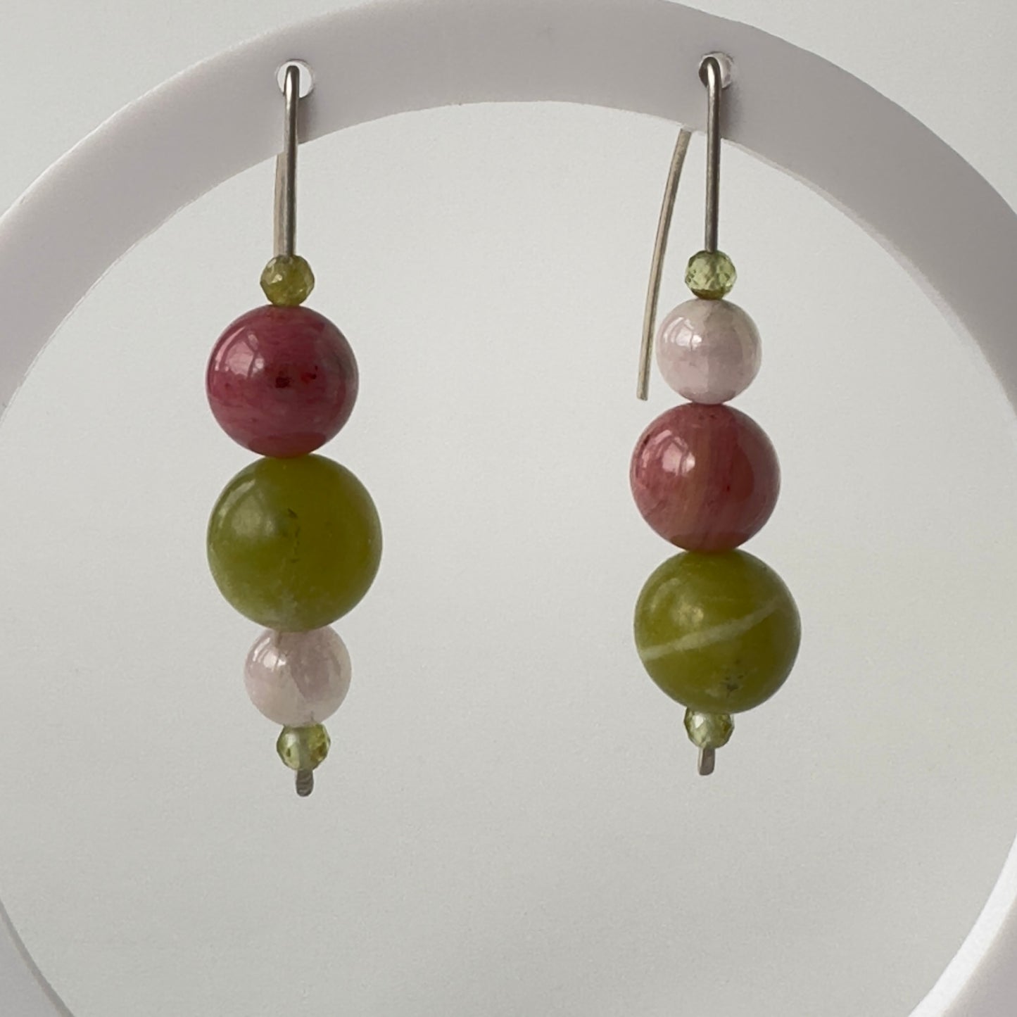 Pair of earrings with green and pink beads on a white background