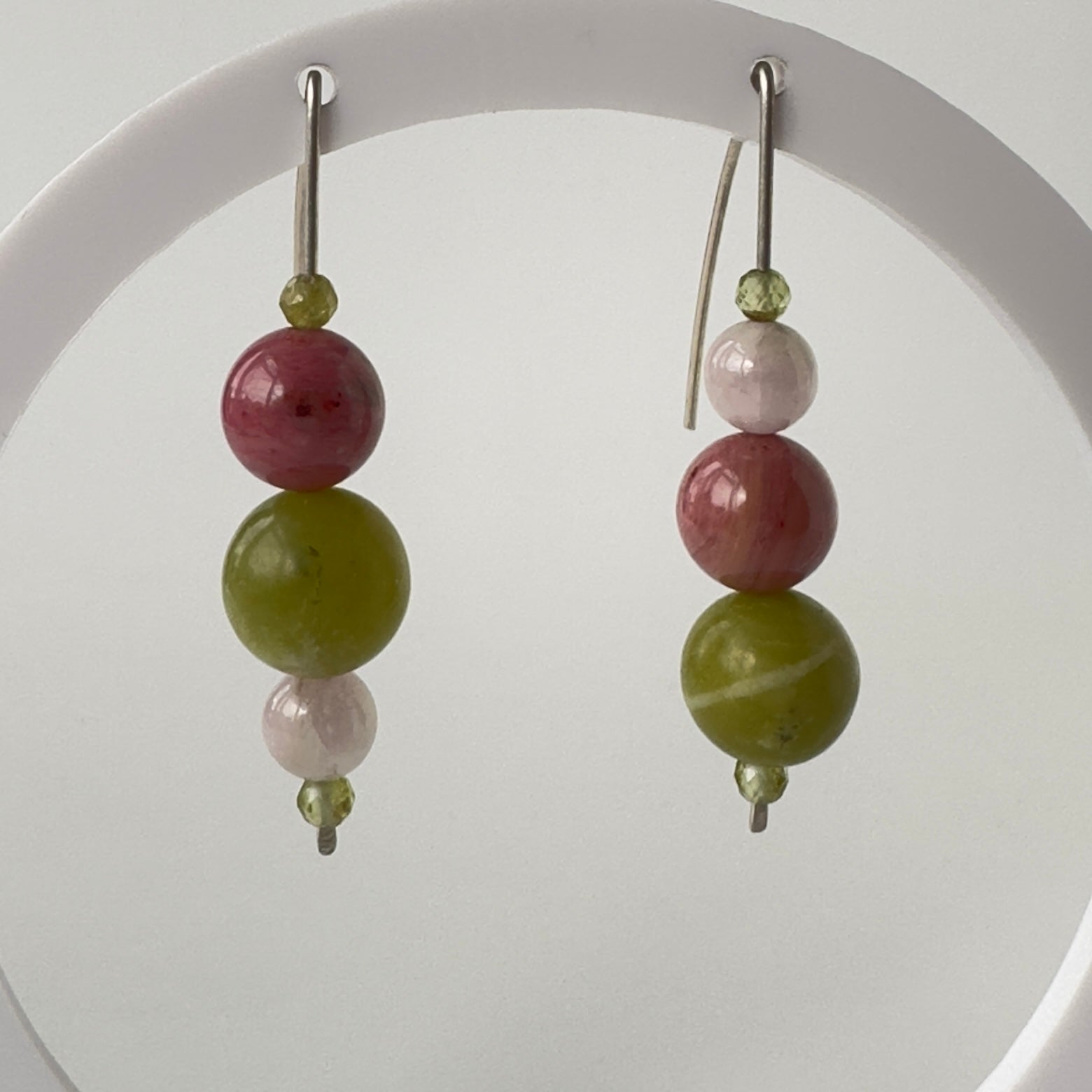 Pair of earrings with green and pink beads on a white background