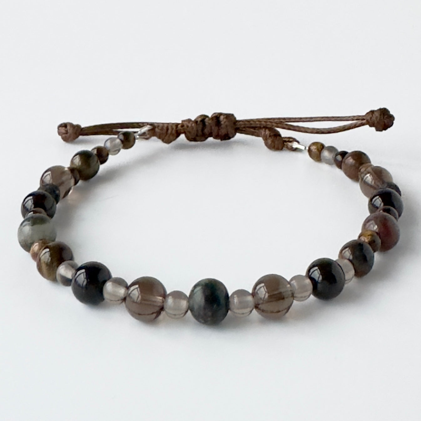 Beaded bracelet with brown cord on a white background
