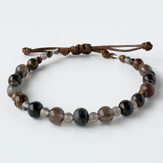 Beaded bracelet with brown cord on a white background