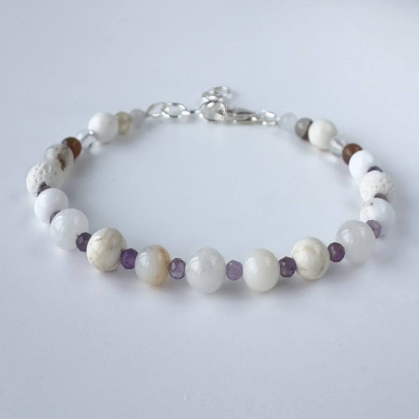 Bracelet with white and brown beads on a light gray background