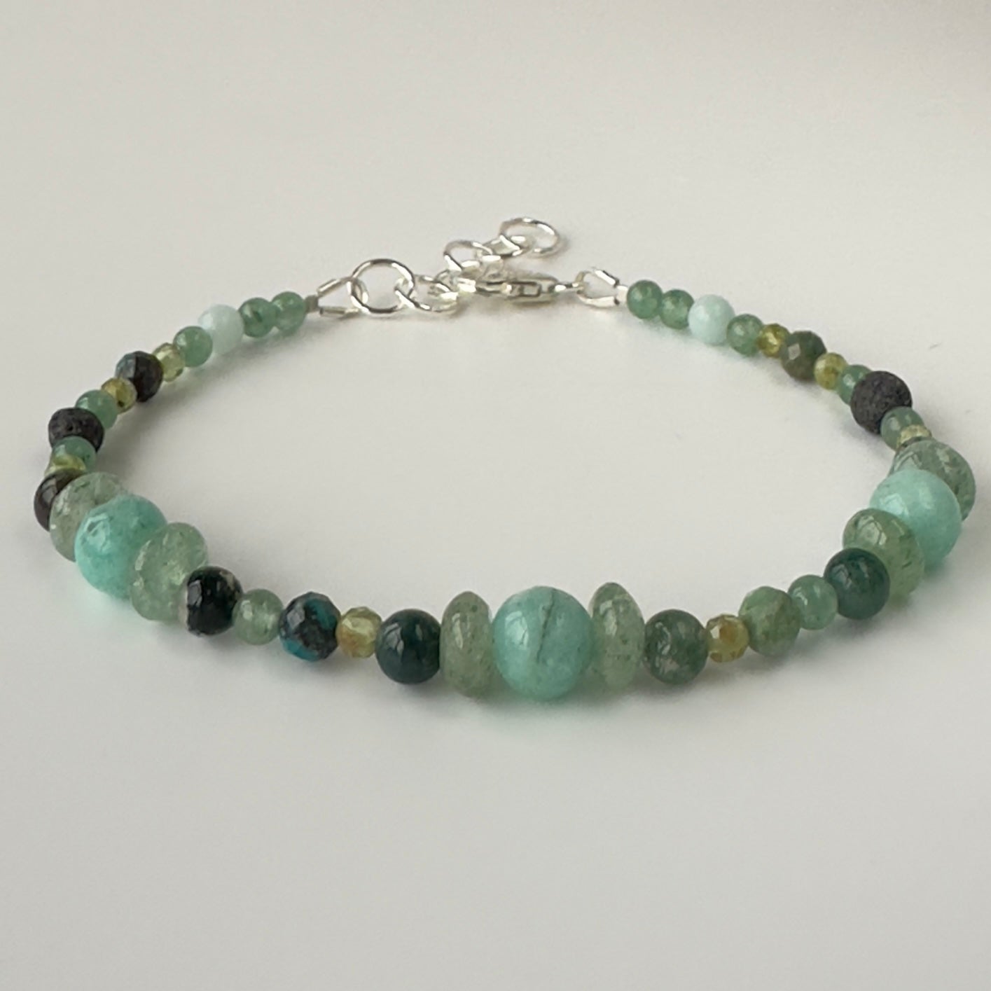 Beaded bracelet with green and black beads on a light gray background