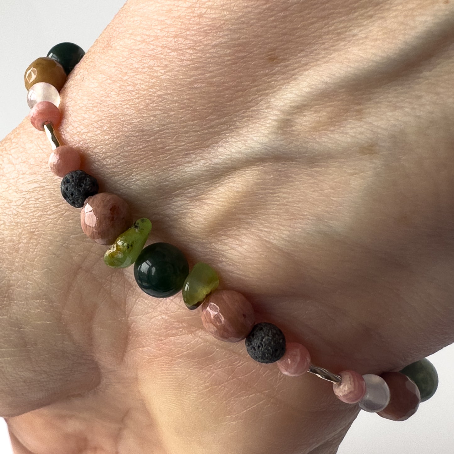 Scorpio BirthstoneHealing Crystal bracelet for Love and Compassion on wrist showing Moss Agate, Chrysoprase, Rhodochrosite, Rhodonite and Lava Stone