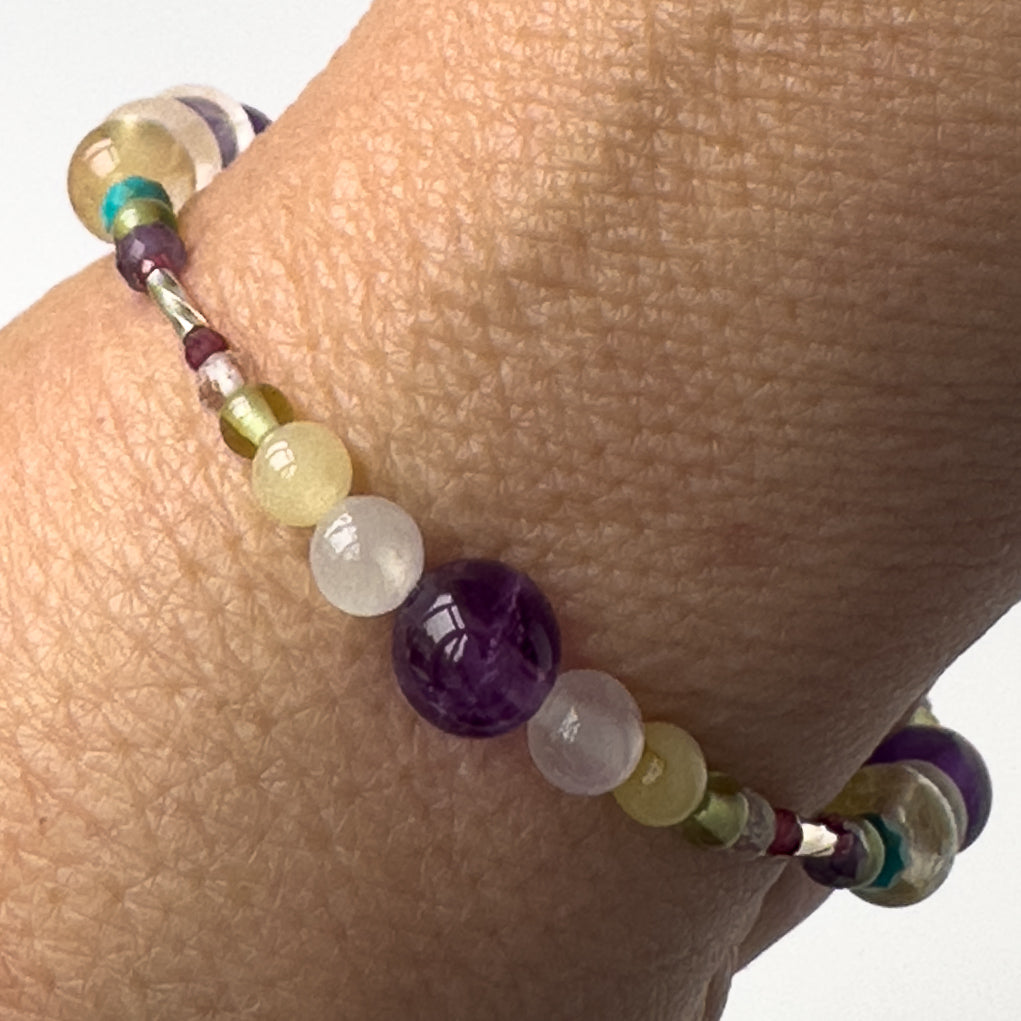 Scorpio Birthstone Healing Crystal bracelet for Determination & Willpower on wrist showing Amethyst, Aragonite, Garnet, Peridot and Selenite