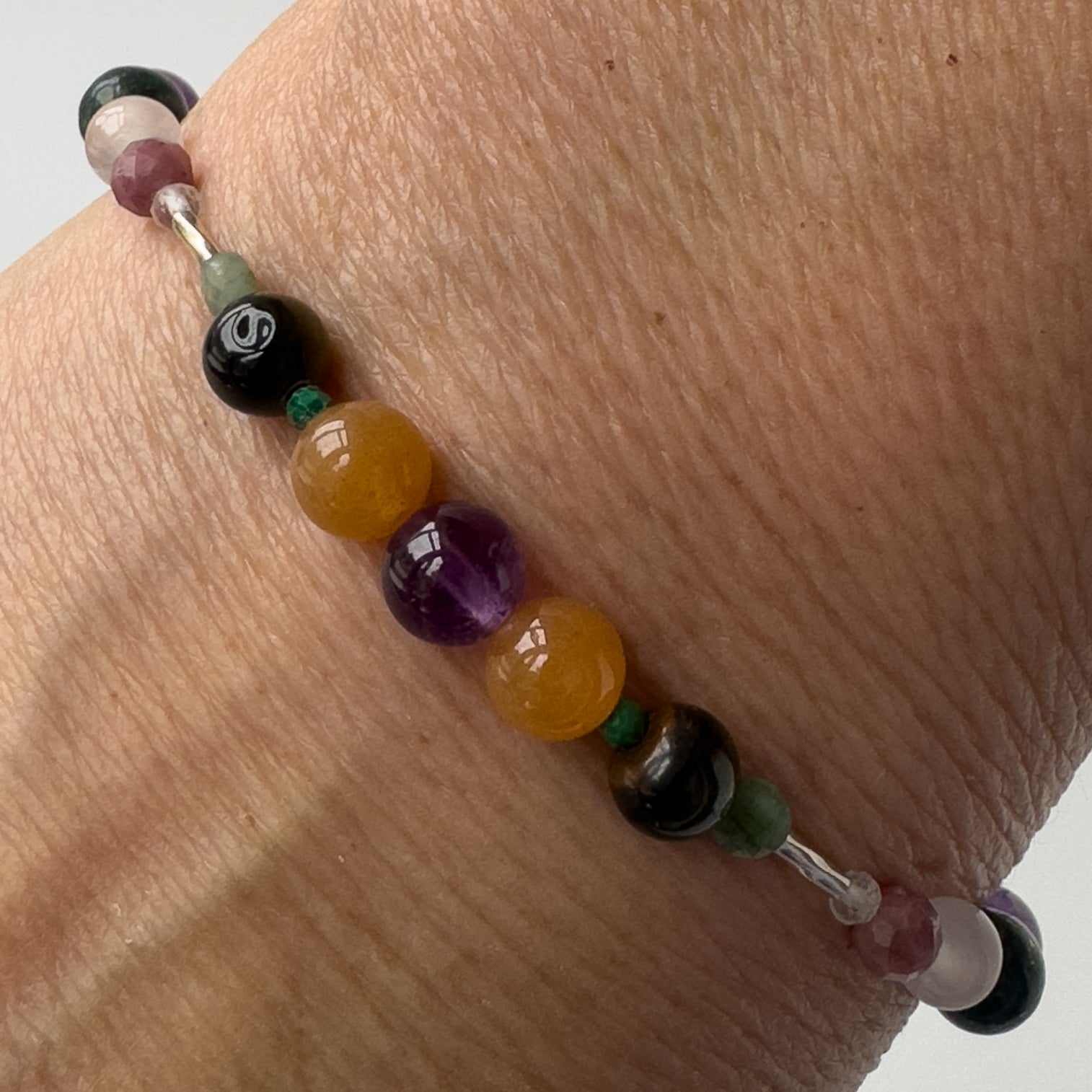 Taurus Crystal Healing bracelet for Grief & Loss on wrist showing Emerald, Amethyst, Malachite, Carnelian and Blue Tiger’s Eye