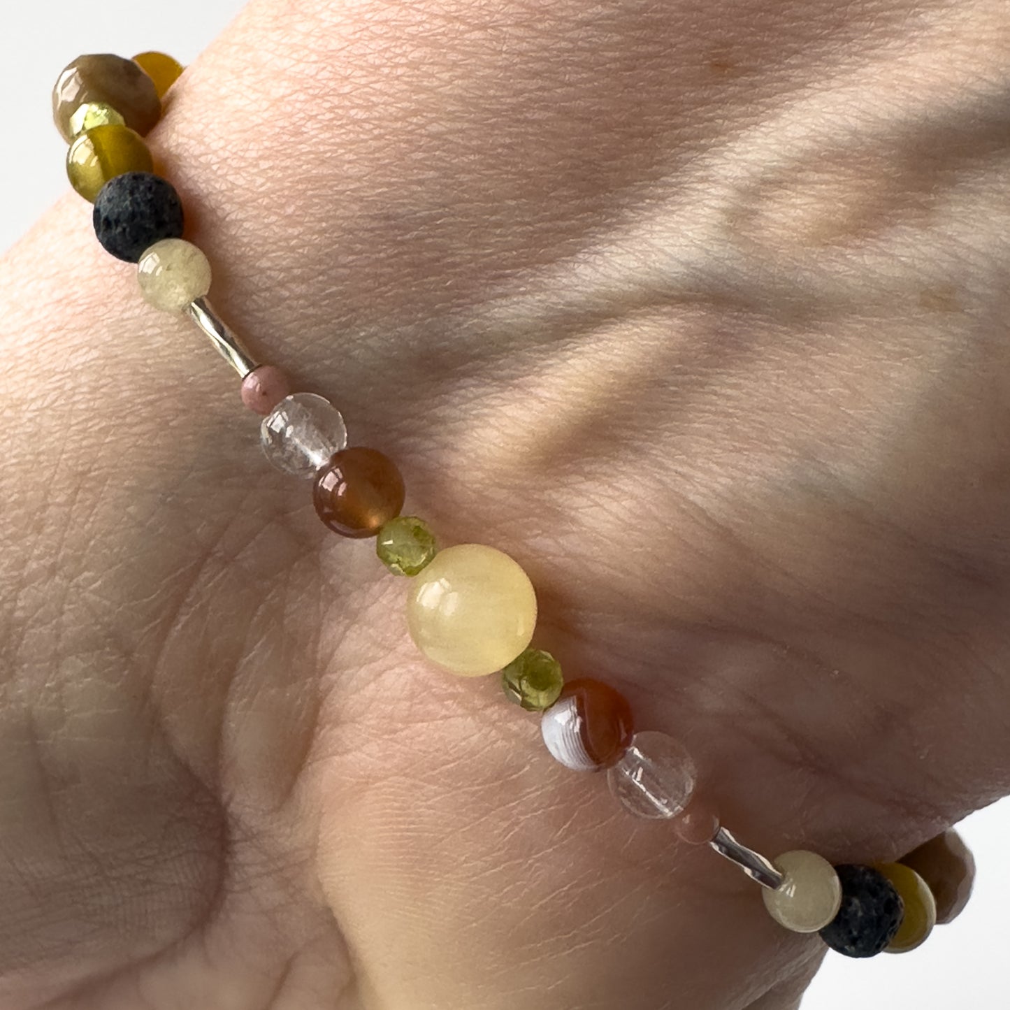 Taurus Birthstone Healing Crystal bracelet for Confidence and Self-esteem on wrist showing Aragonite, Botswana Agate, Peridot, Rhodonite and Clear Quartz 