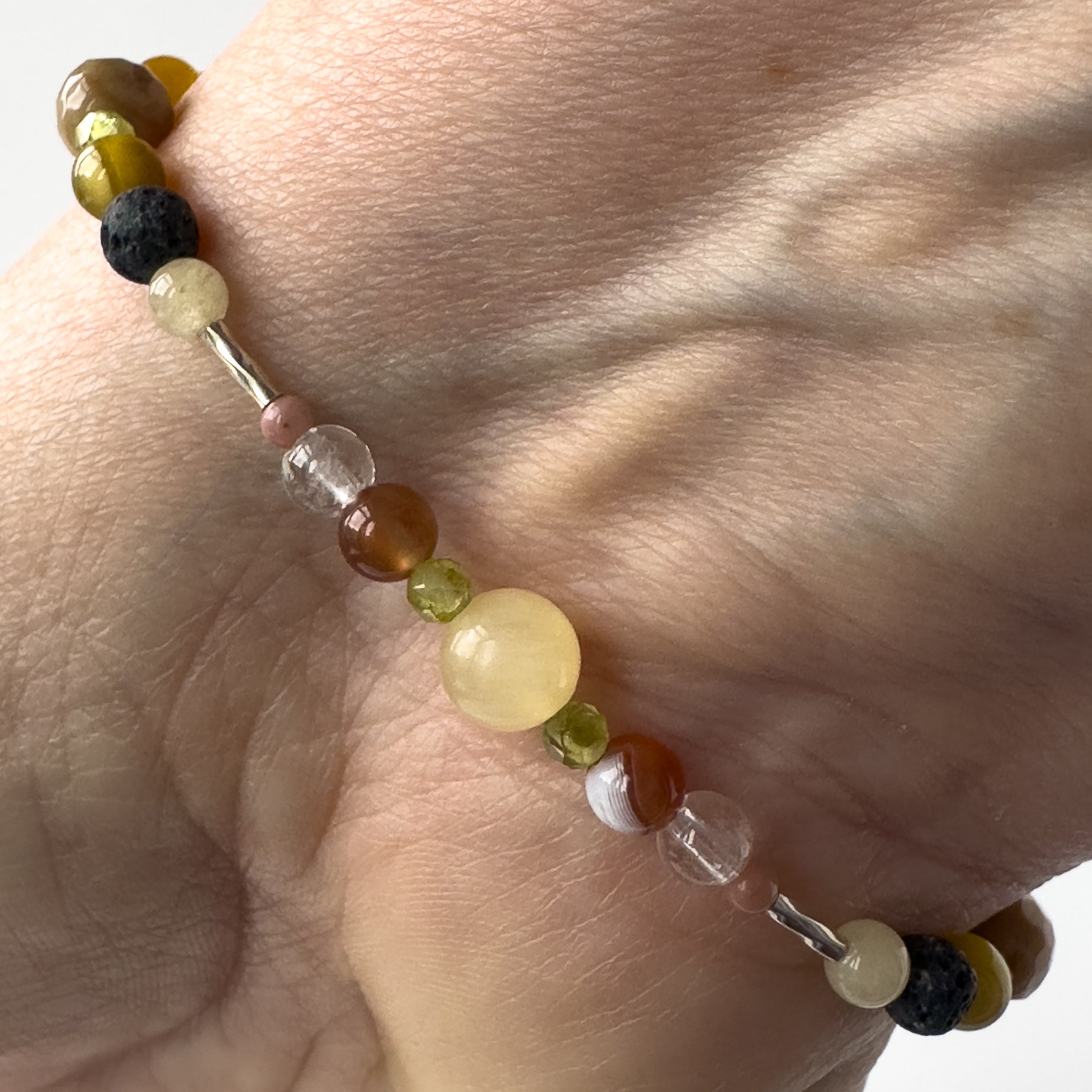 Taurus Birthstone Healing Crystal bracelet for Confidence and Self-esteem on wrist showing Aragonite, Botswana Agate, Peridot, Rhodonite and Clear Quartz 