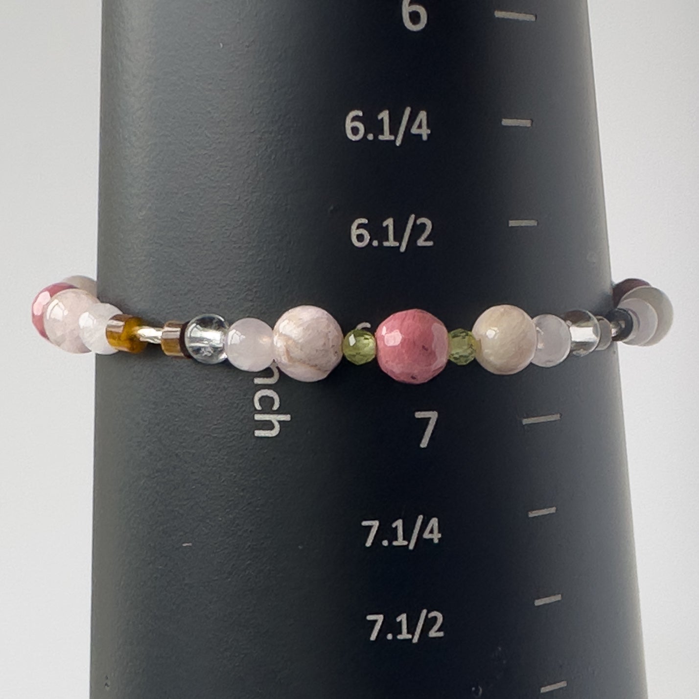 Taurus Birthstone Healing Crystal bracelet for Love and Compassion on mandrel showing Rose Quartz, Peridot, Kunzite, Rhodonite, Tiger’s Eye, Clear Quartz and size of 6.75 inches