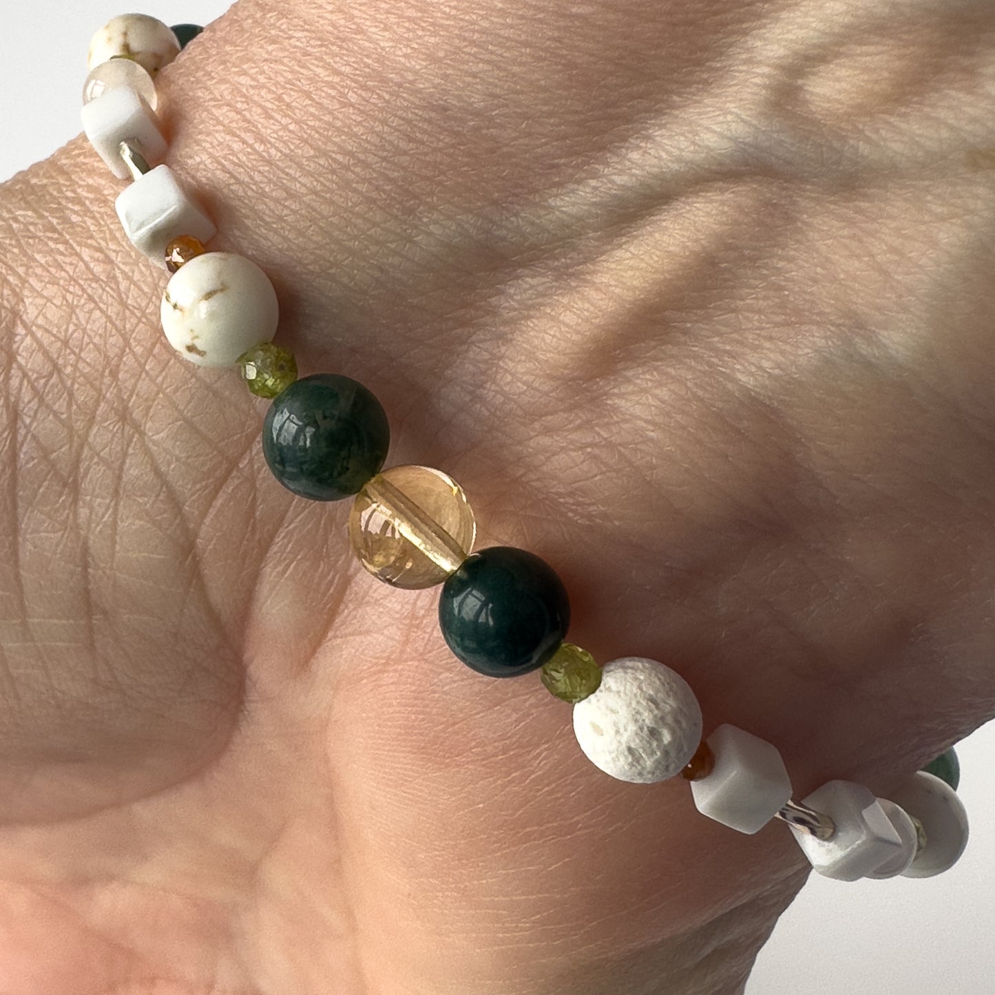 Virgo Birthstone Healing Crystal bracelet for Love and Compassion on wrist showing Citrine, Peridot, Moss Agate, Garnet, Howlite, Magnesite and Lava Stone