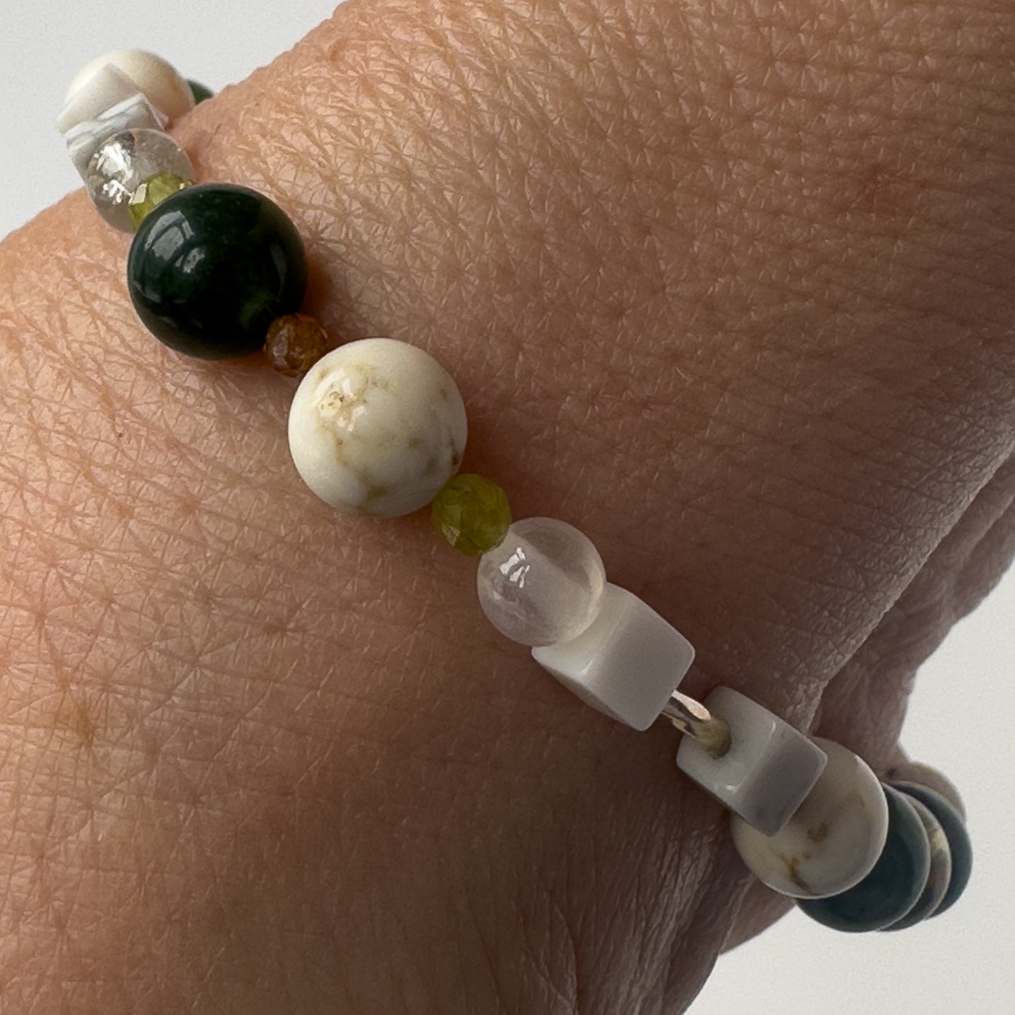 Virgo birthstone Healing Crystal bracelet for Love and Compassion on wrist showing Peridot, Moss Agate, Garnet, Howlite, Magnesite and Selenite